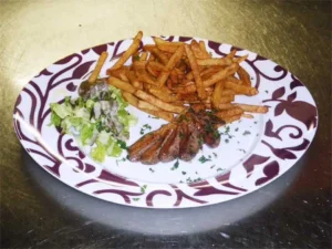 Frites, viande et salade sur assiette.